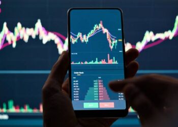 Crypto trader investor broker holding finger using cell phone app executing financial stock trade market trading order to buy or sell cryptocurrency shares thinking of investment risks profit concept.